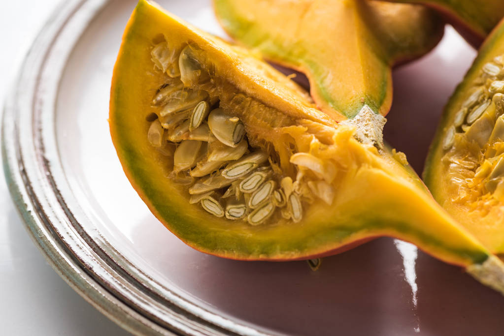 plate with fresh ripe pumpkin quarters with seeds - Photo, Image