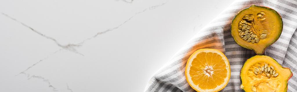 панорамный снимок полосатого полотенца с апельсином и тыквой на мраморной поверхности
 - Фото, изображение