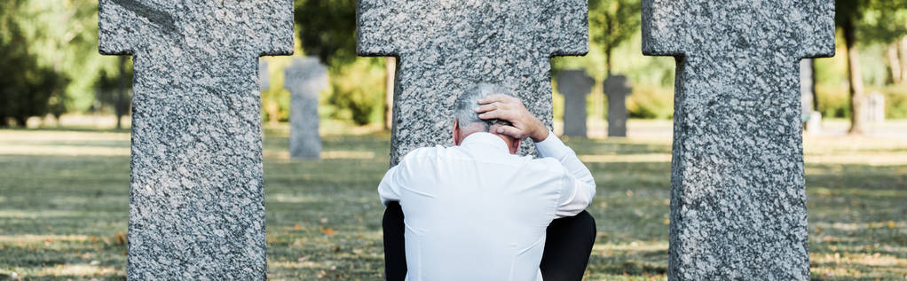 панорамный снимок пожилого человека, сидящего возле гробниц
  - Фото, изображение