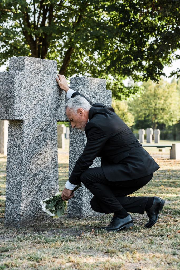 uomo barbuto sconvolto mettere fiori vicino tomba nel cimitero
  - Foto, immagini