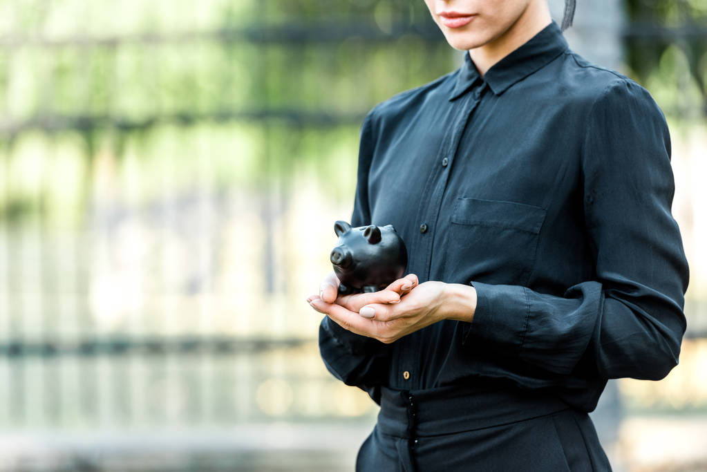 Ausgeschnittene Ansicht einer Frau mit schwarzem Sparschwein  - Foto, Bild