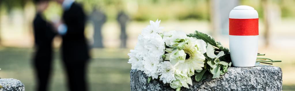 panoramic shot of white flowers and cemetery urn on tombstone - Photo, Image