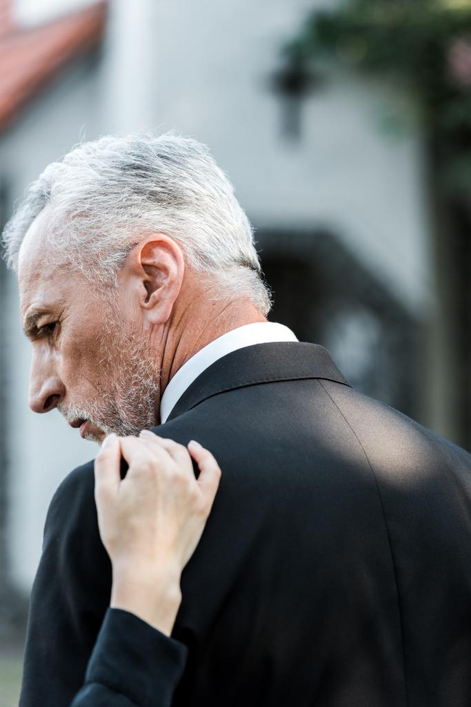 przycięte widok kobiety dotykając starszy mężczyzna z siwych włosów na pogrzebie  - Zdjęcie, obraz