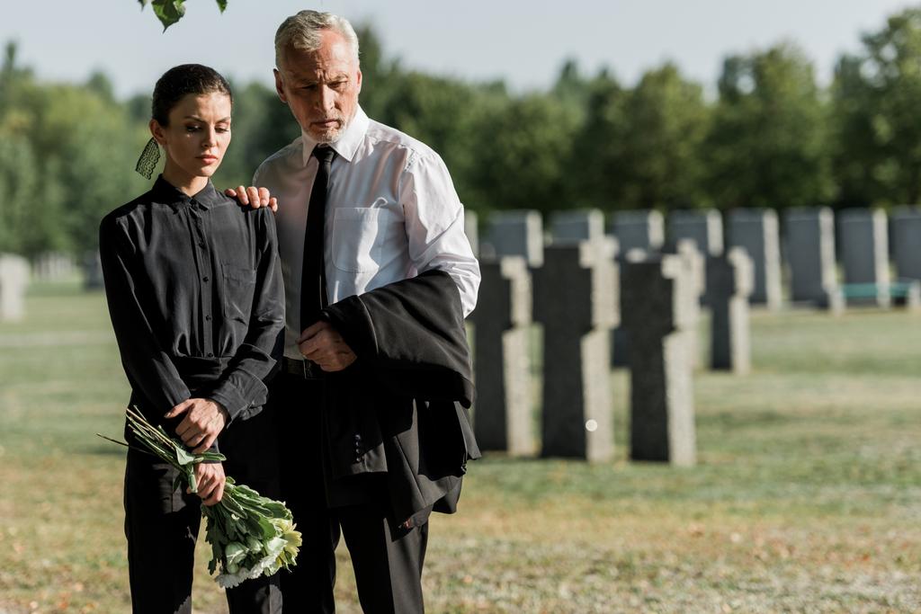 старший мужчина, стоящий с привлекательной женщиной с цветами на похоронах
 - Фото, изображение