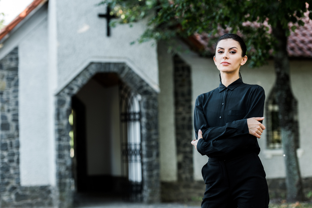 atraktivní žena stojící u překřížené paže blízko kostela  - Fotografie, Obrázek
