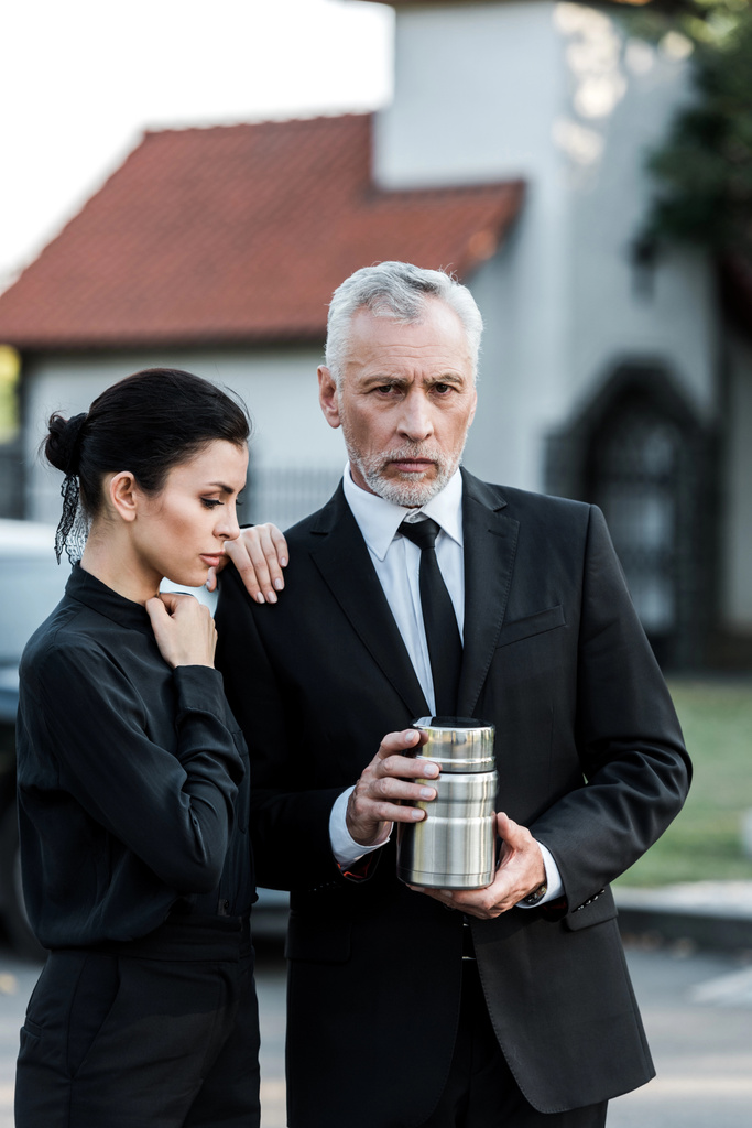 upset woman standing near bearded senior man with mortuary urn  - Photo, Image
