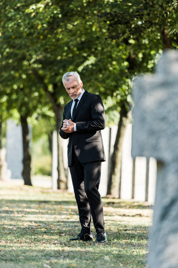 избирательный фокус грустного пожилого человека, стоящего на кладбище
  - Фото, изображение