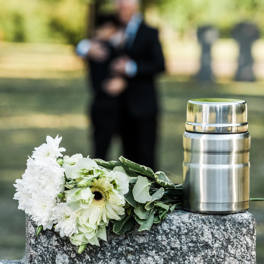 selective focus of white flowers and mortuary urn on tombstone - Photo, Image