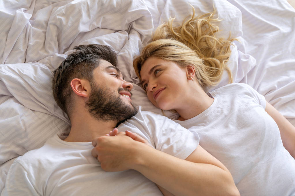 Усміхнена пара лежить разом у спальні
 - Фото, зображення