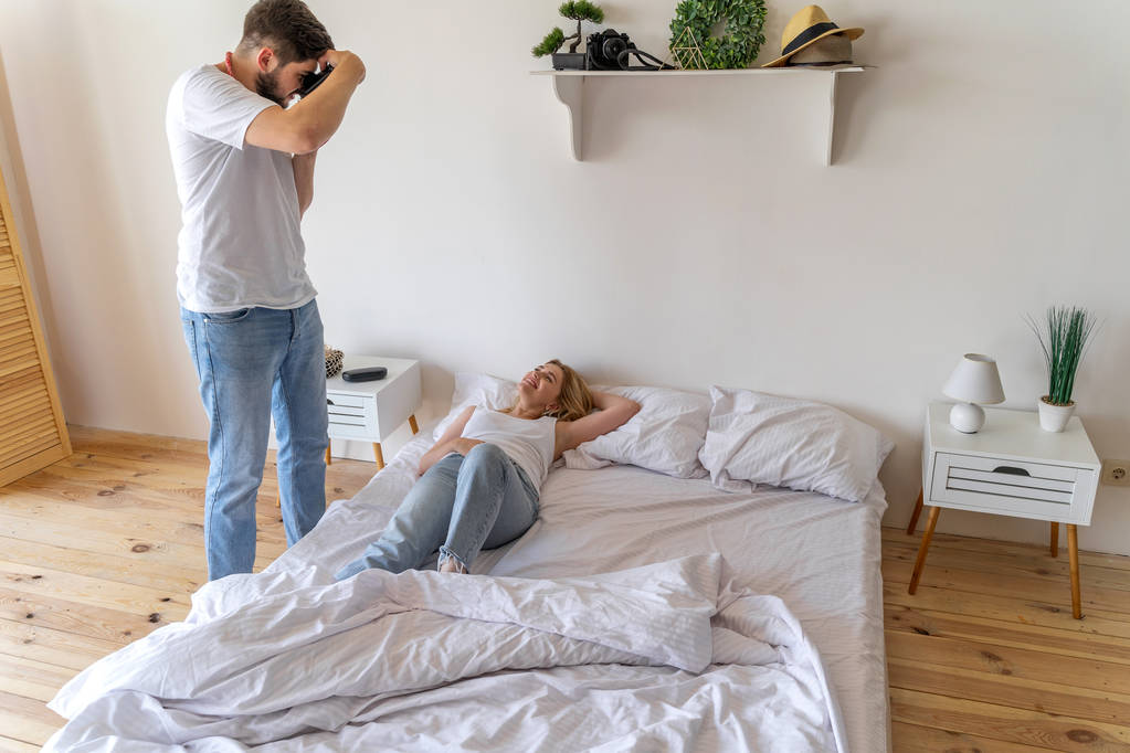 Jovem está fotografando sua namorada na cama
 - Foto, Imagem