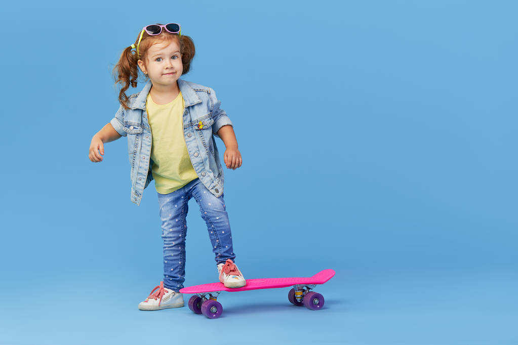 Criança menina elegante legal com skate sobre fundo azul
 - Foto, Imagem