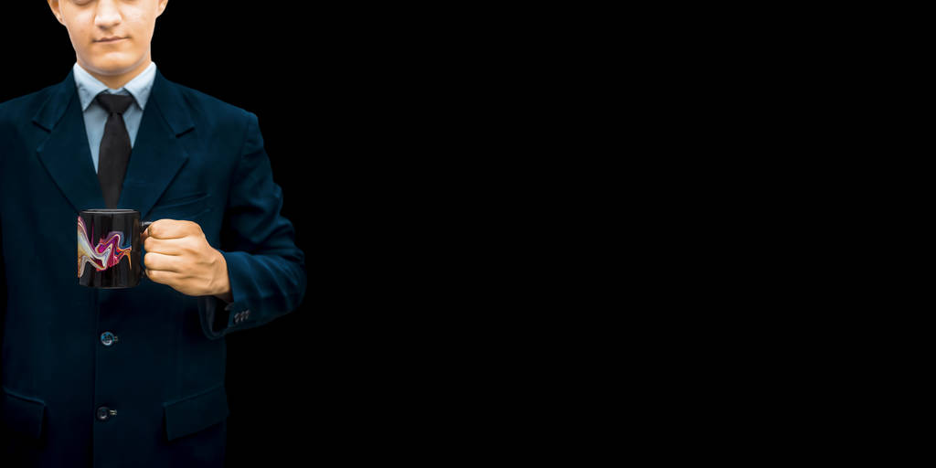 Funcionário de escritório vestindo um terno de cor azul e posando com uma xícara de café em suas mãos isolado em um fundo de cor preta
. - Foto, Imagem