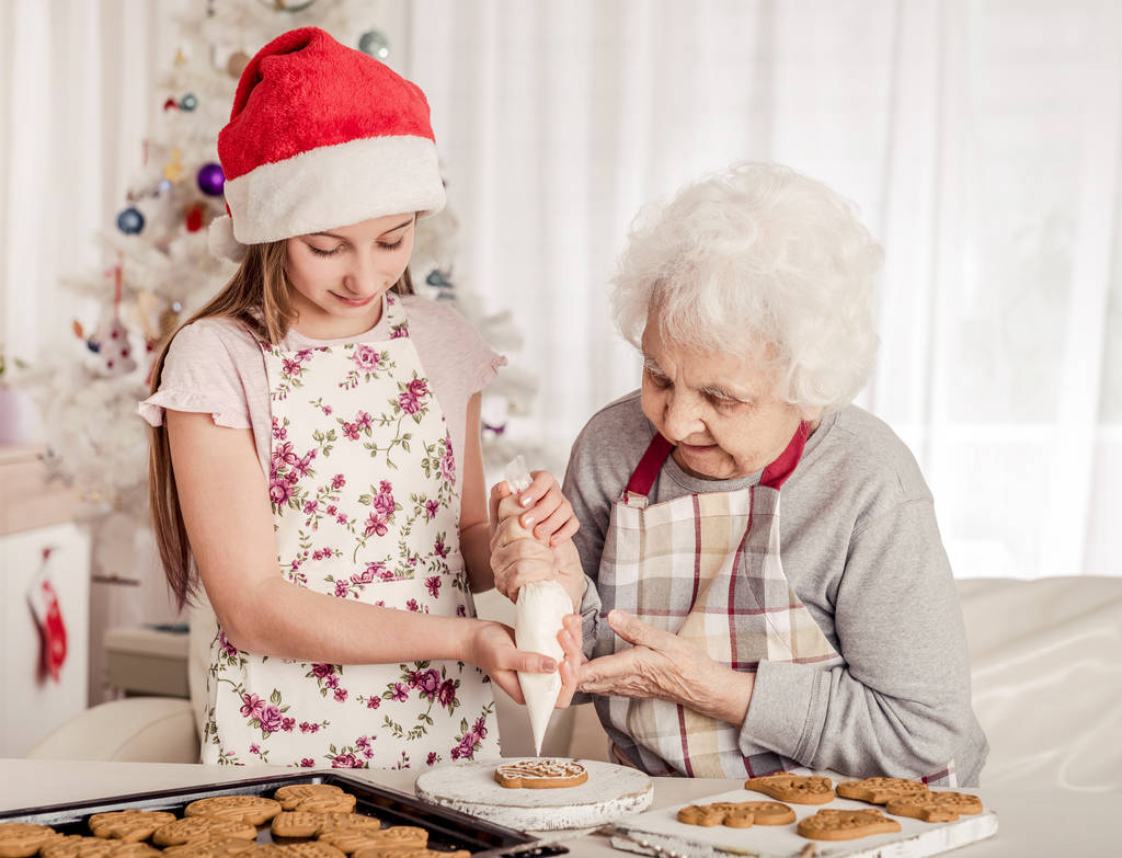 Großmutter mit Enkelin dekoriert Plätzchen - Foto, Bild