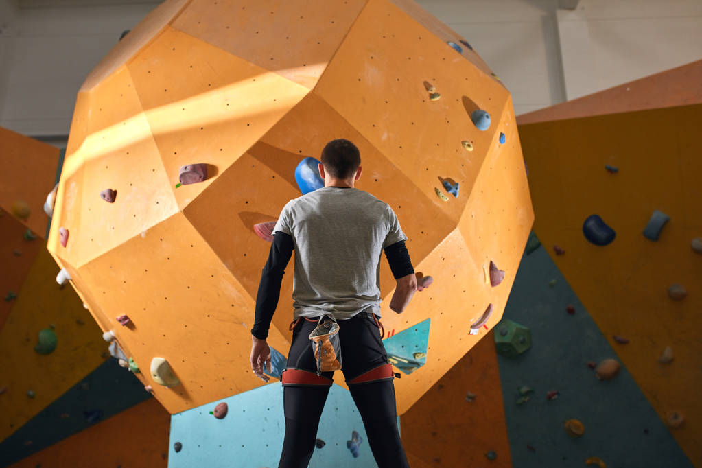 Мотивований атлетичний чоловік без передпліччя стоїть поруч зі стіною для скелелазіння
 - Фото, зображення