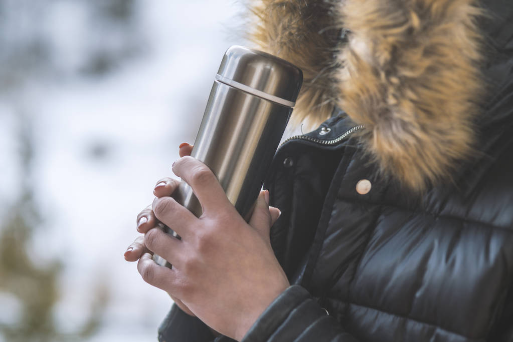 horký čaj nebo káva z termosky v ženských rukou na zimních forech - Fotografie, Obrázek