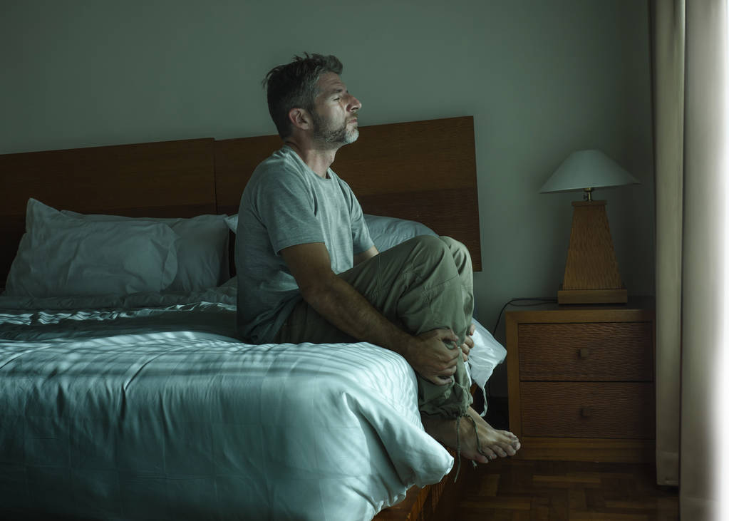yatakta feeli oturan yakışıklı adam dramatik yaşam tarzı portre - Fotoğraf, Görsel