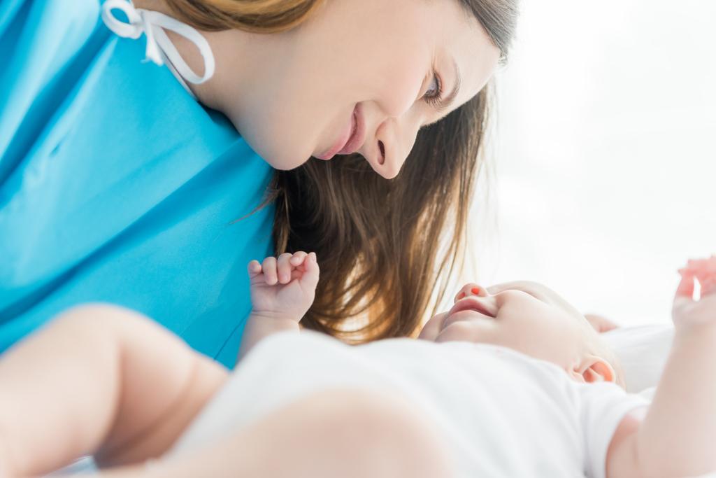επιλεκτική εστίαση της ελκυστικής μητέρας κοιτάζοντας το μωρό της στο νοσοκομείο  - Φωτογραφία, εικόνα