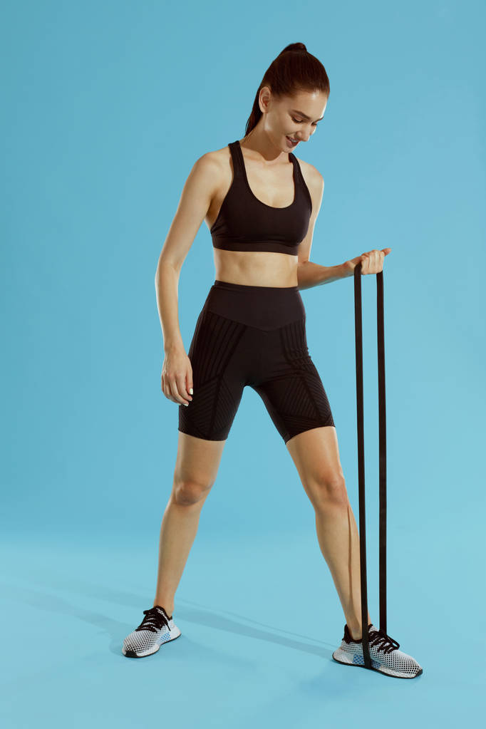 Mujer deportiva en ropa deportiva haciendo ejercicio con banda de resistencia
  - Foto, imagen