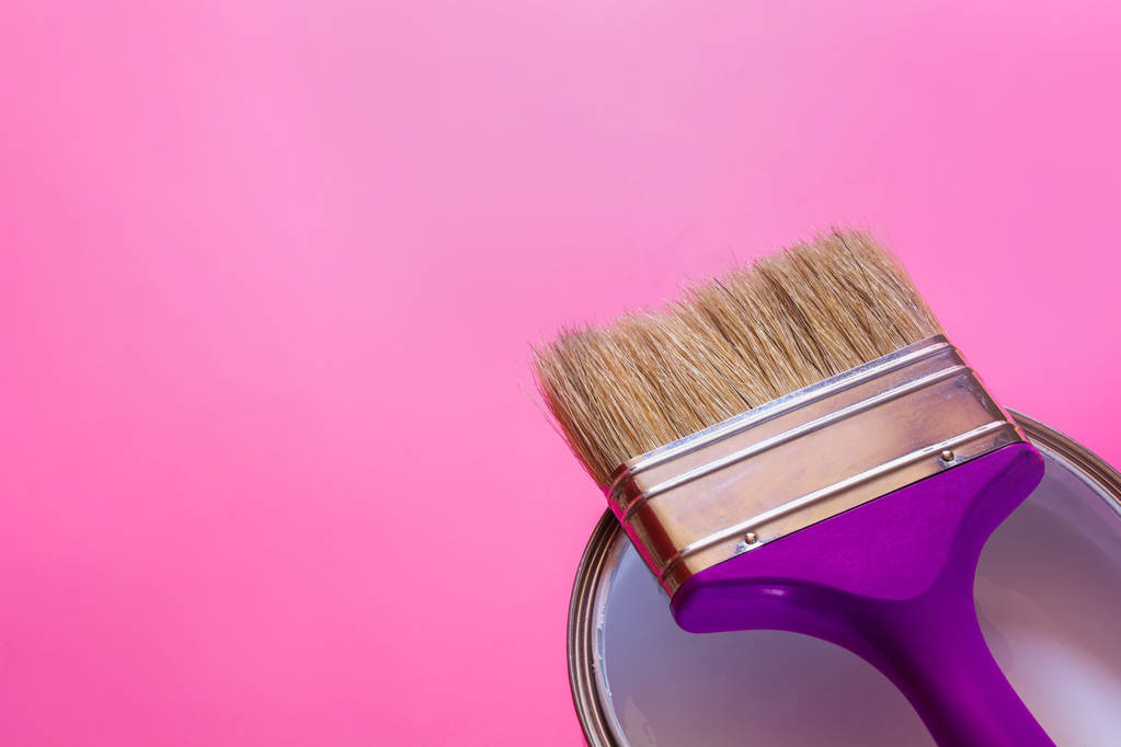 Pincel púrpura con lata abierta de pintura blanca sobre fondo rosa. Concepto de tendencia
. - Foto, Imagen