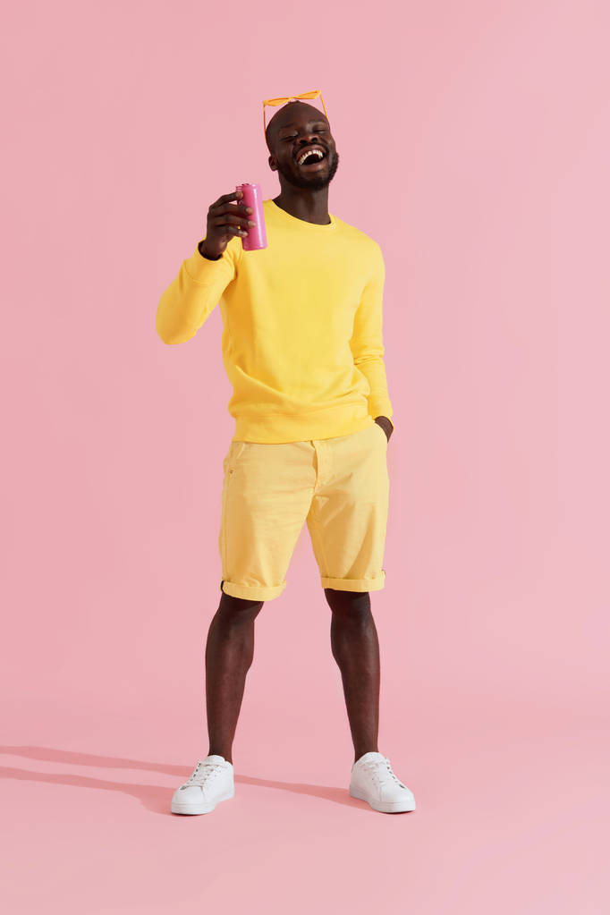 Pić. Szczęśliwy czarny człowiek w żółtym mody ubrania z miękkim napojem - Zdjęcie, obraz