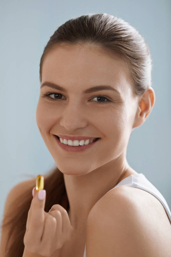 Vitamina. Mujer sonriente con omega 3 píldora, cápsula de aceite de pescado
 - Foto, Imagen