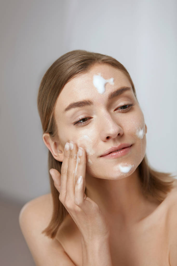 Cara cuidados com a pele. Mulher aplicando limpador facial no close-up do rosto
 - Foto, Imagem