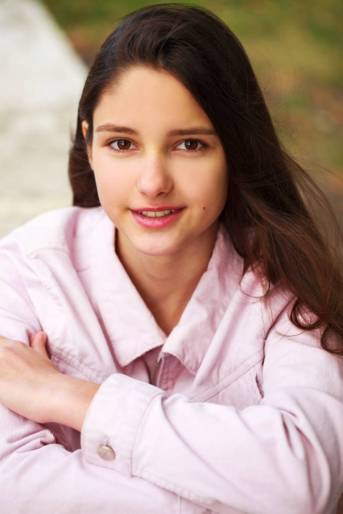 Πορτρέτο ενός νεαρού μελαχρινή κορίτσι σε ροζ παλτό σε ένα φόντο o - Φωτογραφία, εικόνα