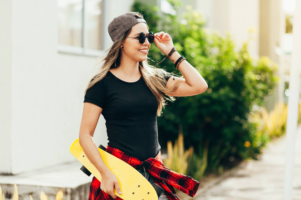 Портрет улыбающейся юной скейтбордистки со своим скейтбордистом
 - Фото, изображение
