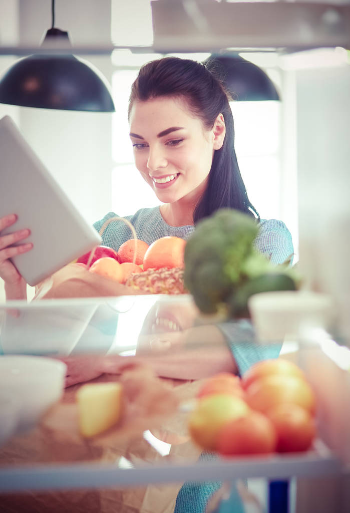 Lächelnde Frau holt frisches Obst aus dem Kühlschrank, gesundes Ernährungskonzept - Foto, Bild