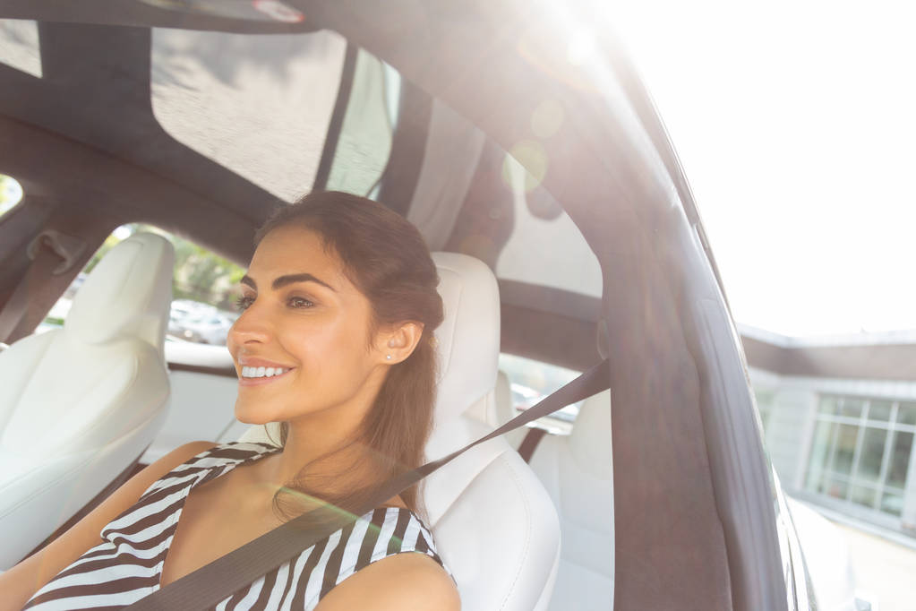 Aantrekkelijke jonge vrouw glimlachend tijdens het rijden auto in de stad - Foto, afbeelding