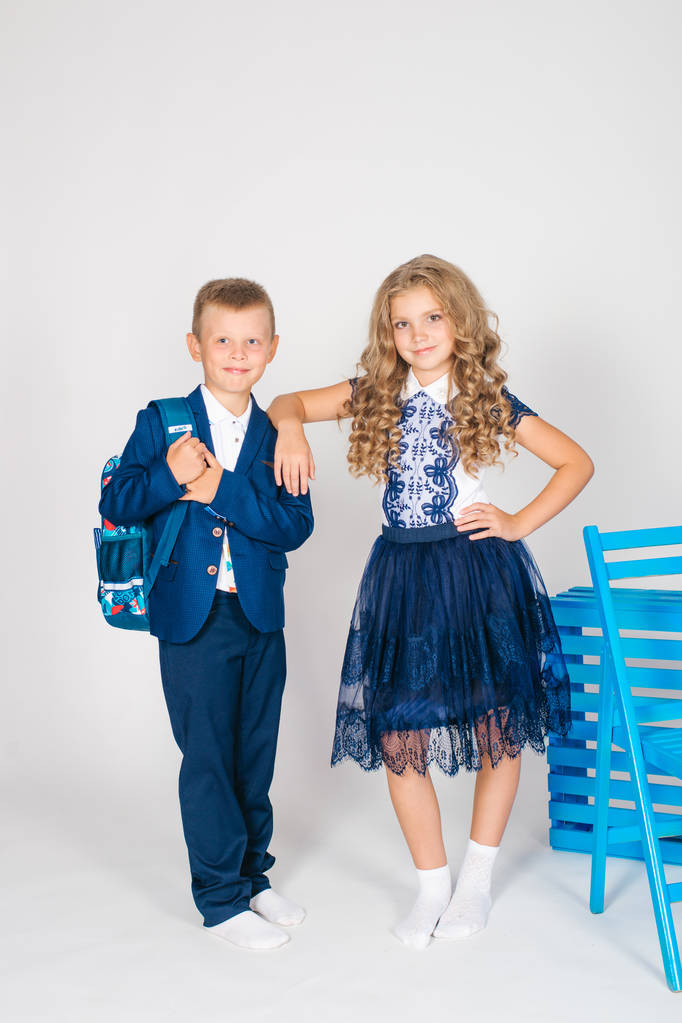 Boy and girl schoolchildren in fashionable school clothes with a school bag on a white background - Photo, Image