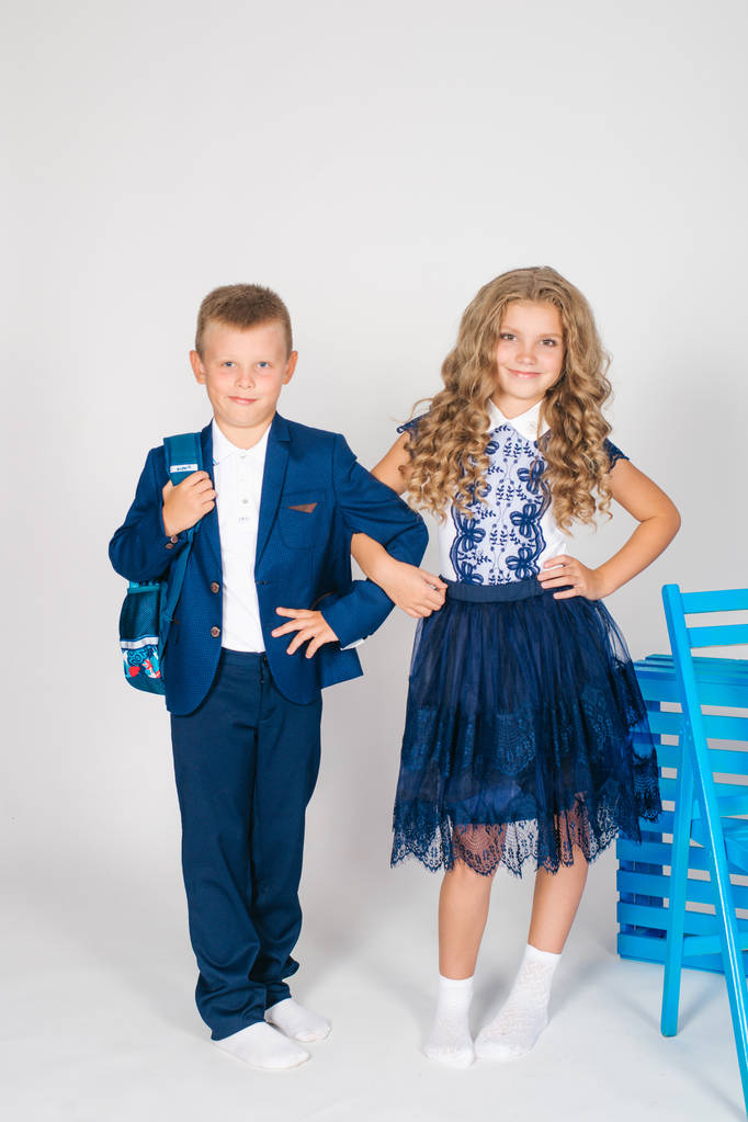 Boy and girl schoolchildren in fashionable school clothes with a school bag on a white background - Photo, Image