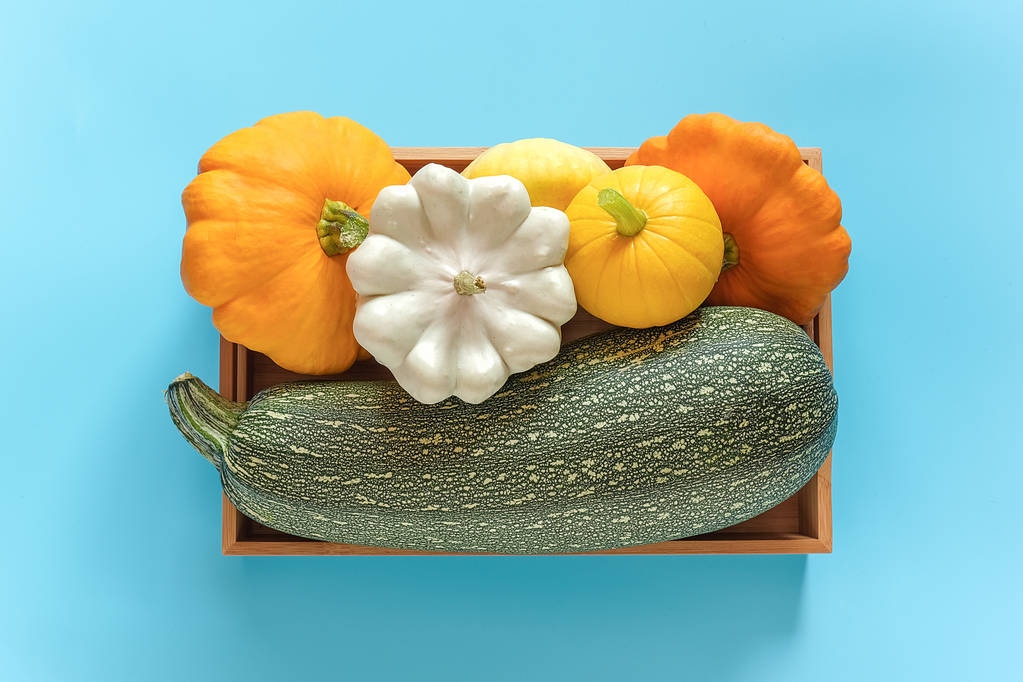 Betakarítás színes különböző zöldségek tökfélék sütőtök, cukkini, squash egy fadobozban kék háttér. Felülnézet lapos feküdt - Fotó, kép