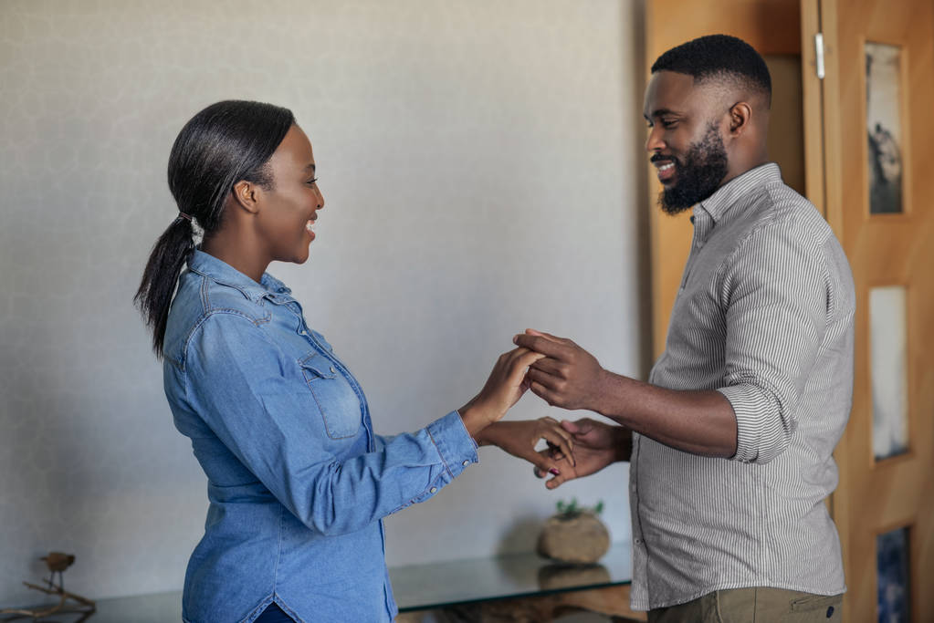 Усміхнений молодий афроамериканець пари грайливо танцюють рука об руку разом у своїй вітальні вдома - Фото, зображення