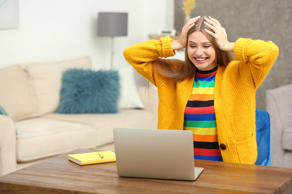 Boldog fiatal nő játszik online szerencsejáték-használó laptop otthon - Fotó, kép