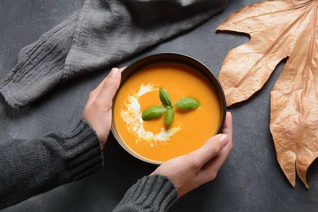 Bol de soupe à la crème de citrouille et de carotte dans les mains. Automne chaud concept de soupe végétalienne
 - Photo, image