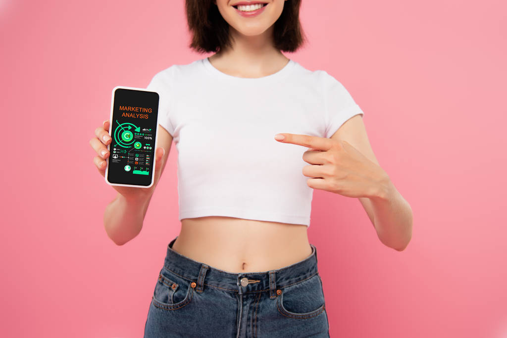vista cortada de menina apontando com o dedo para o smartphone com aplicativo de análise de marketing isolado em rosa
 - Foto, Imagem