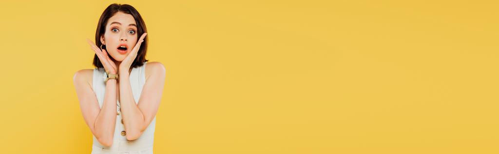 plano panorámico de impactada chica elegante con las manos cerca de la cara aislado en amarillo
 - Foto, imagen