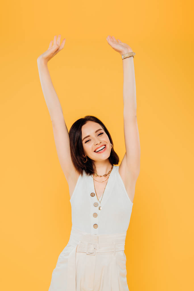 smiling elegant girl with hands in air isolated on yellow - Photo, Image