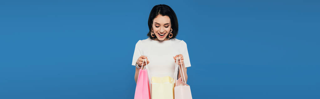 panoráma szemcsésedik-ból izgatott elegáns asszony-ban ruha tárolás bevásárló zsákok elszigetelt-ra kék - Fotó, kép