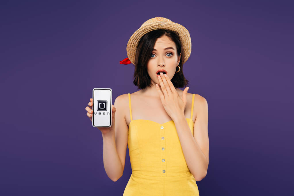 キエフ、ウクライナ - 2019年7月3日:アイデアジェスチャーを示すわら帽子の女の子と紫色に隔離されたUberのロゴを持つスマートフォンを保持 - 写真・画像