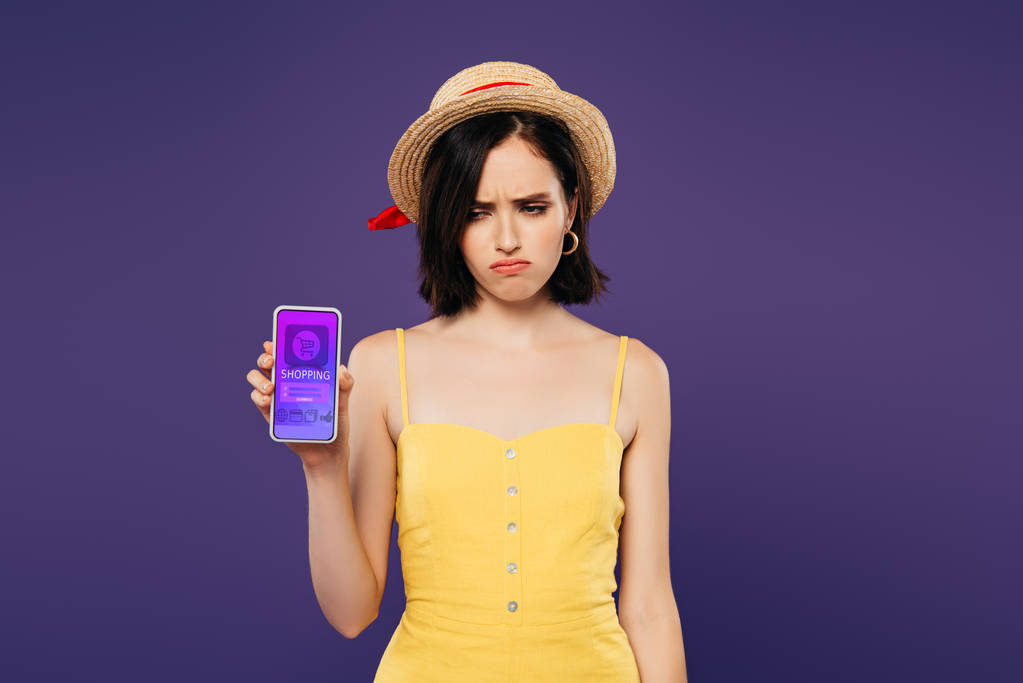 紫色に隔離されたオンラインショッピングアプリでスマートフォンを保持するわら帽子の悲しいかわいい女の子  - 写真・画像