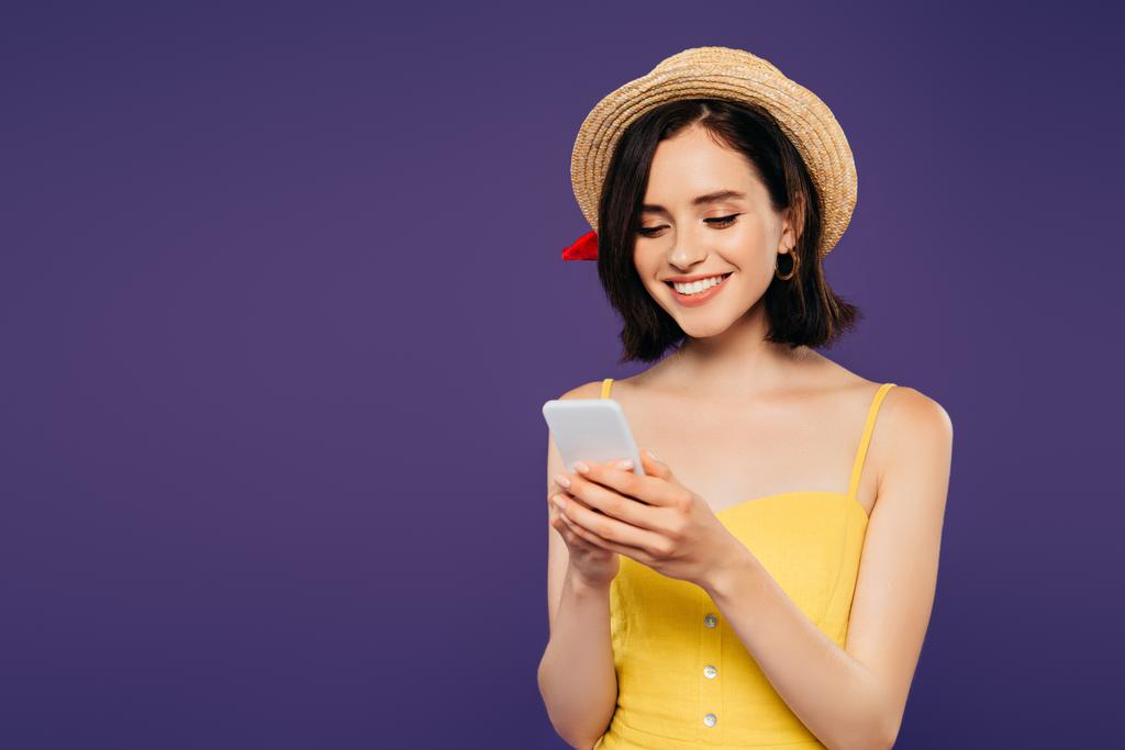 smiling girl in straw hat using smartphone isolated on purple  - Photo, Image
