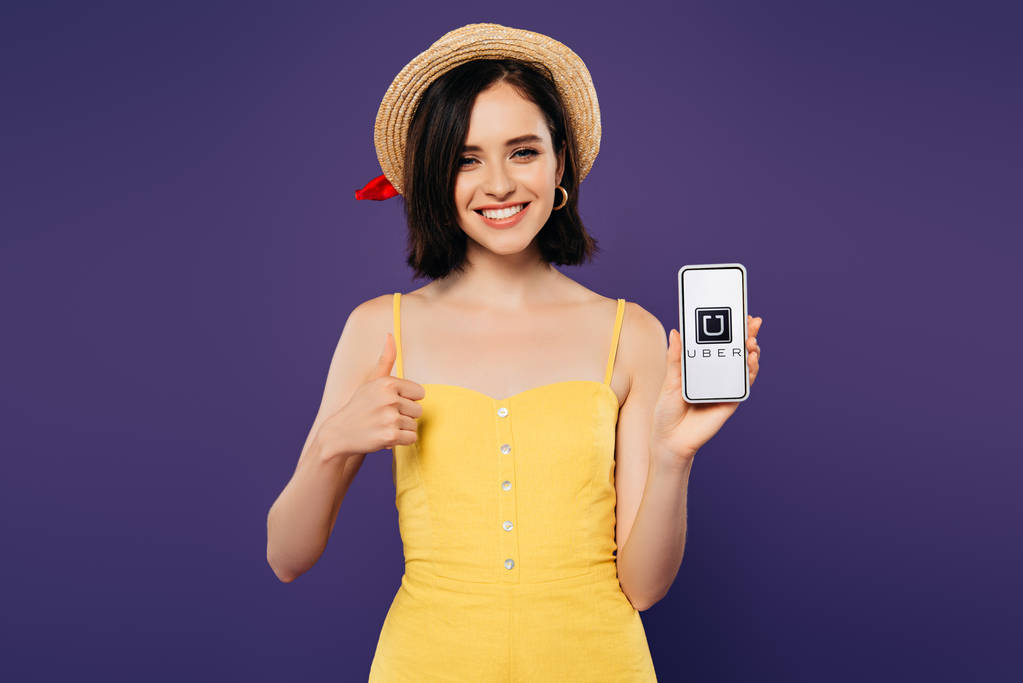 kyiv, ukraine - 3. Juli 2019: Lächelndes hübsches Mädchen mit Strohhut zeigt Daumen hoch, während es Smartphone mit uber-App in lila hält  - Foto, Bild