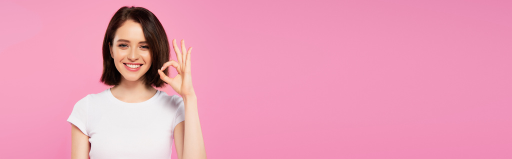 tiro panorâmico de sorrir menina bonita mostrando sinal ok isolado em rosa
 - Foto, Imagem