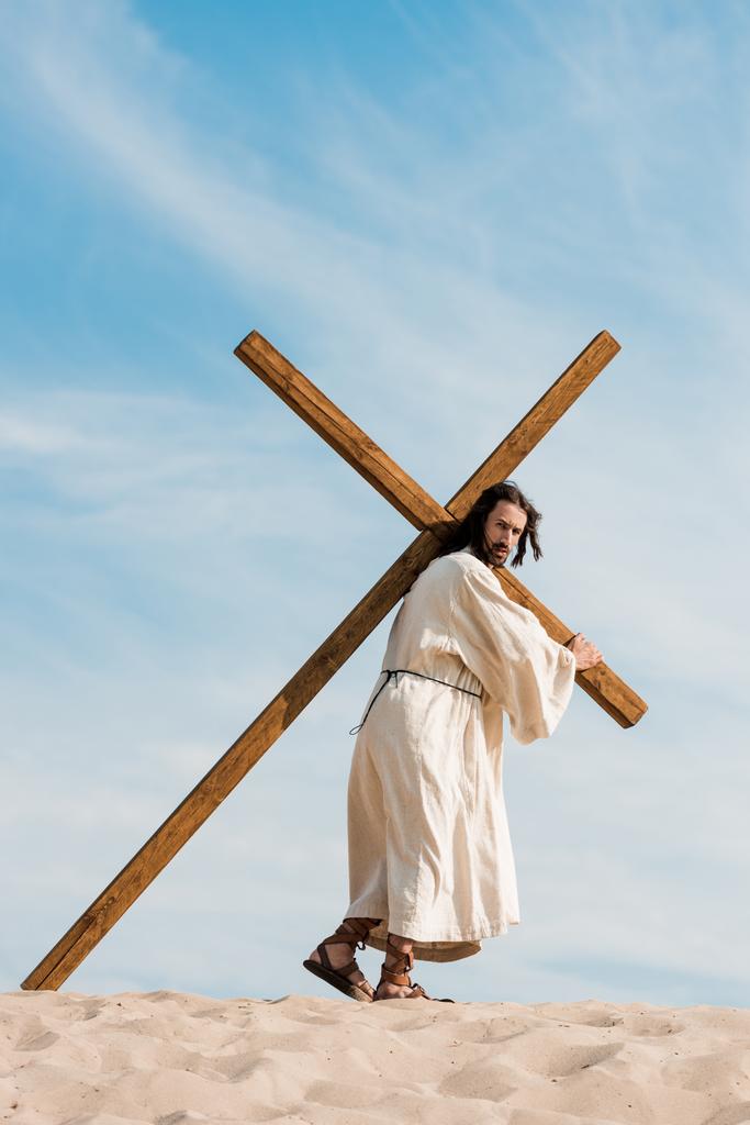 Jésus marchant avec croix en bois dans le désert
  - Photo, image