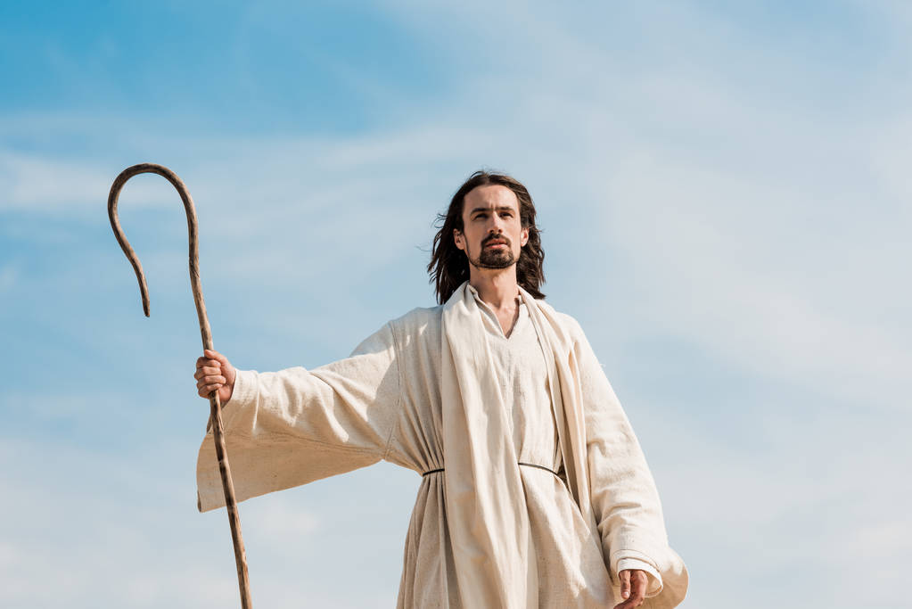 Jesus segurando cana de madeira contra o céu azul e nuvens
 - Foto, Imagem