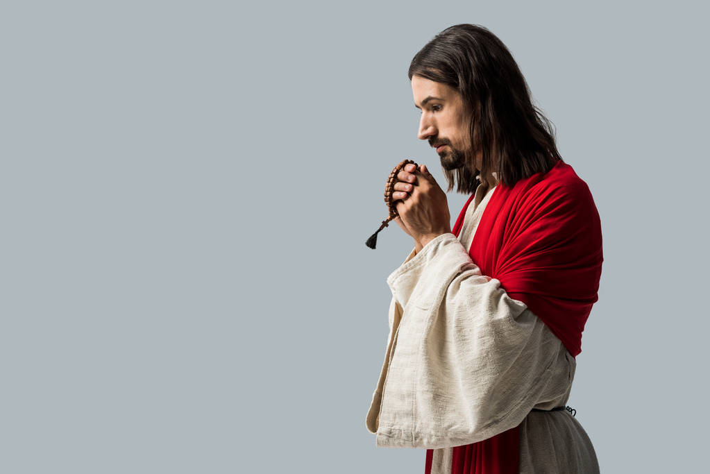 灰色の上に孤立した祈りをしながら、ロザリオビーズを持つ宗教的な男  - 写真・画像