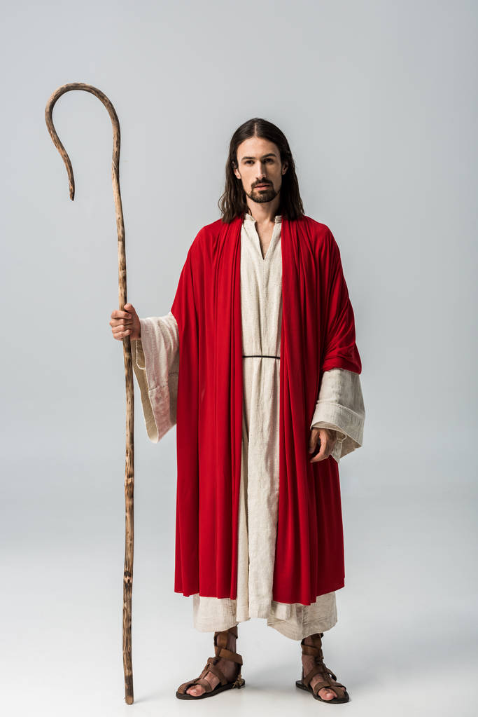 красивий чоловік в халаті Ісуса тримає дерев'яну тростину на сірому
 - Фото, зображення
