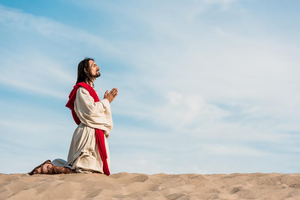 homem orando de joelhos no deserto na areia dourada
  - Foto, Imagem